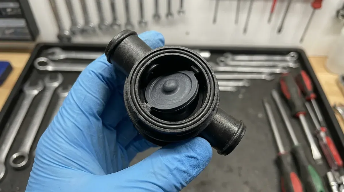 dishwasher check valve held in gloved hand showing rubber flapper